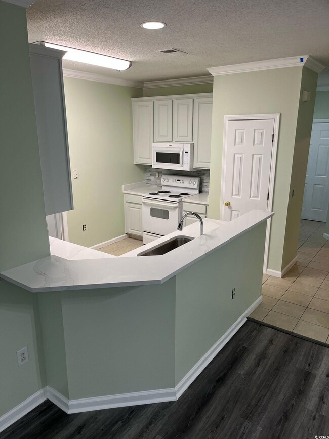 Kitchen with ornamental molding, white appliances,