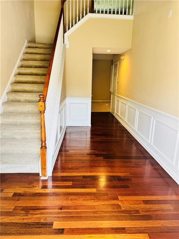 Stairway with wood finished floors, a wainscoted w