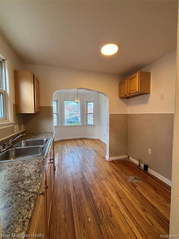Kitchen featuring brown cabinetry, arched walkways, and light wood-style floors