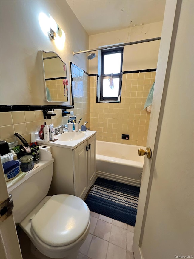 Bathroom featuring vanity, tile walls, tile patterned floors, and shower / bathtub combination