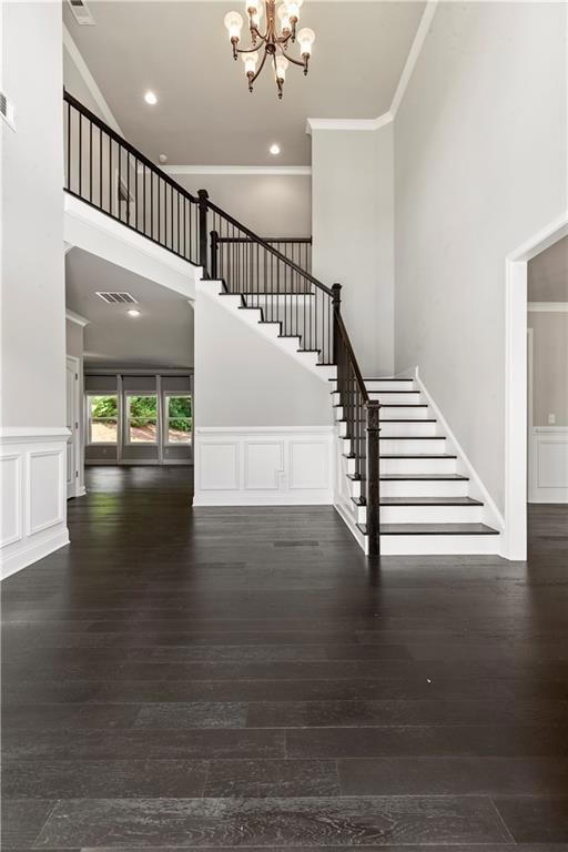 Foyer entrance featuring ornamental molding, stairs, a chandelier, hardwood / wood-style flooring, and a high ceiling