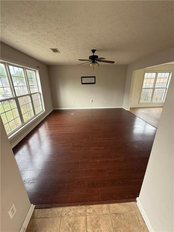 Empty room with wood finished floors, a ceiling fan, and a textured ceiling