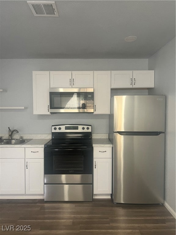Kitchen with appliances with stainless steel finishes, white cabinets, and light countertops