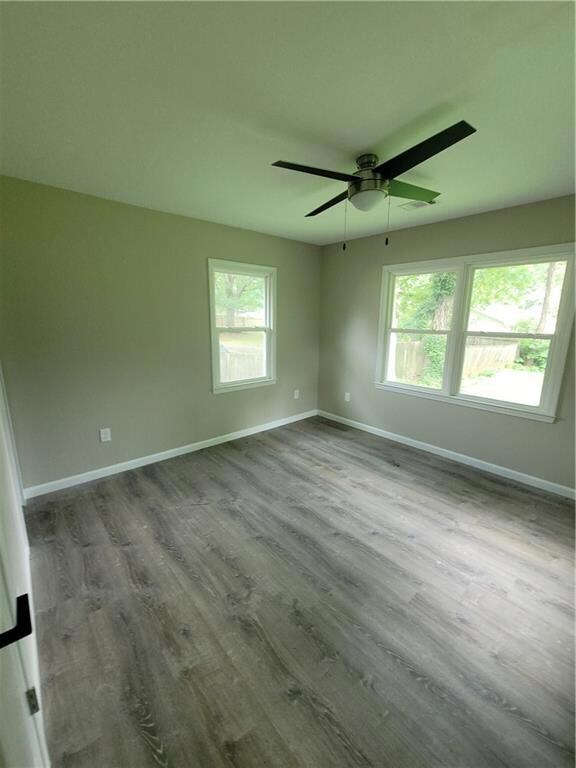 Spare room featuring dark wood-type flooring and ceiling fan