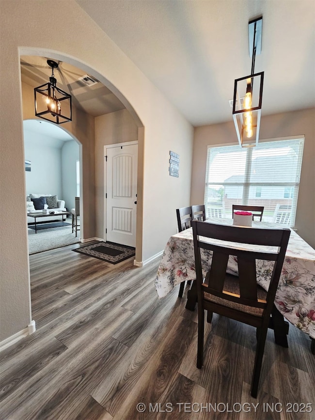 Dining space featuring arched walkways, wood finished floors, a chandelier, and baseboards