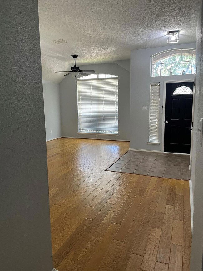 Tiled entryway featuring ceiling fan, a textured ceiling, and lofted ceiling