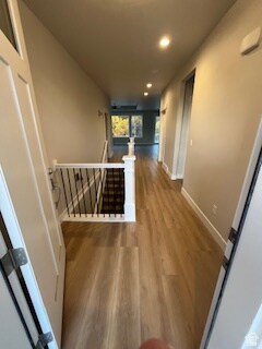Hall featuring dark wood-style floors, an upstairs landing, and recessed lighting