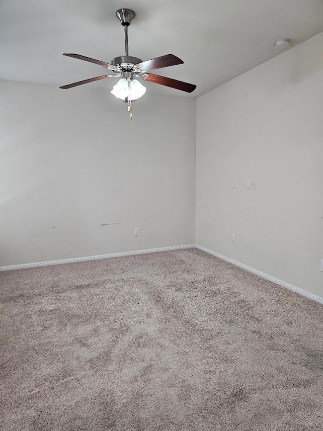 Carpeted empty room with a ceiling fan, a smoke d