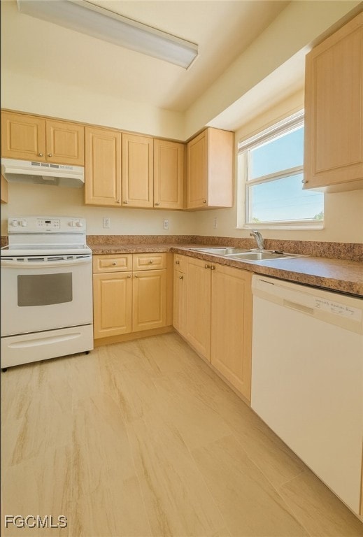 Kitchen featuring white appliances, light brown cabinetry, under cabinet range hood, and light countertops