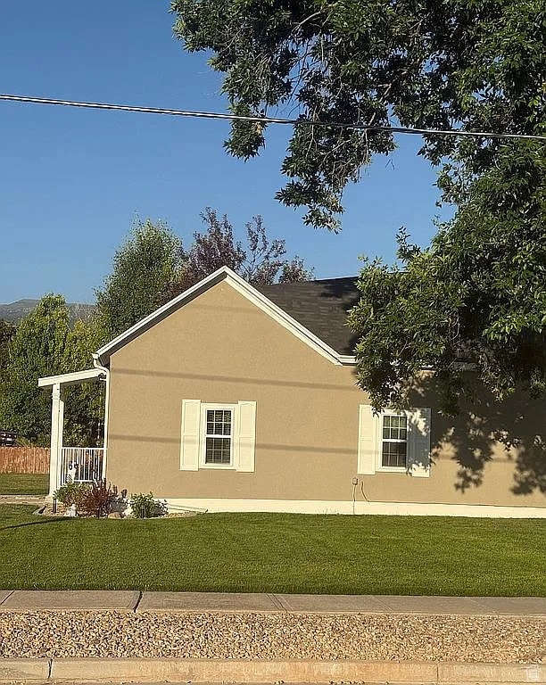 View of side of property with a lawn and stucco siding