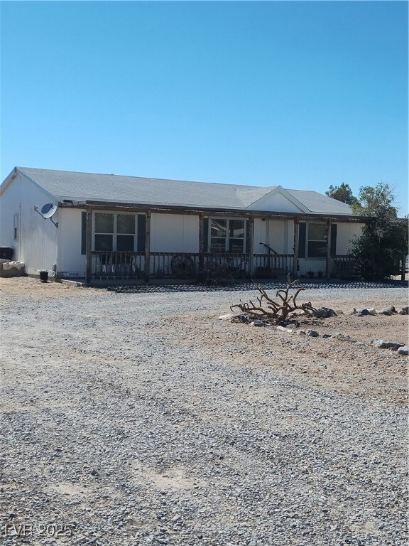 View of front of home with a porch and gravel driv