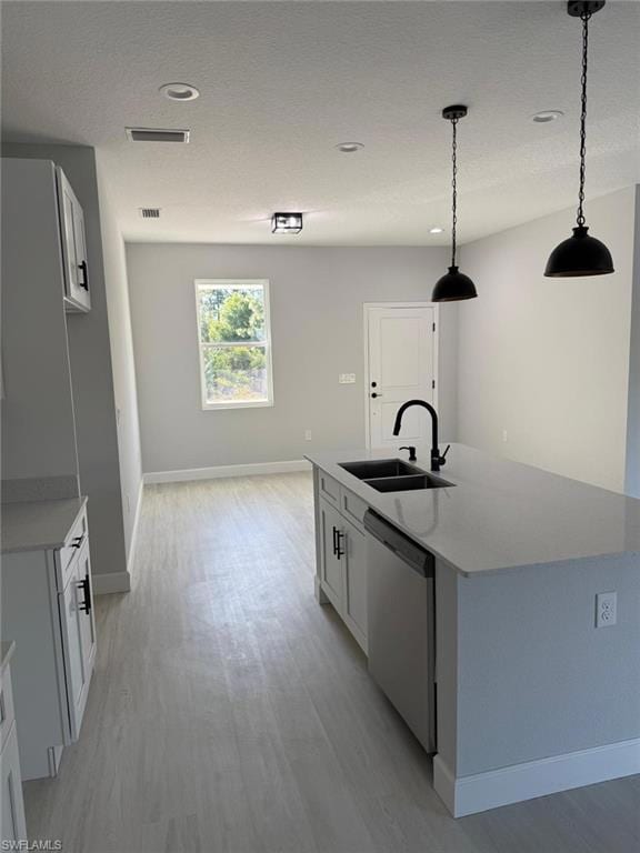 Kitchen with stainless steel dishwasher, a sink, baseboards, light wood-style floors, and an island with sink