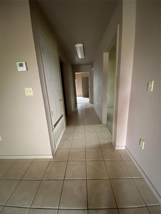 Hallway with baseboards and light tile patterned f