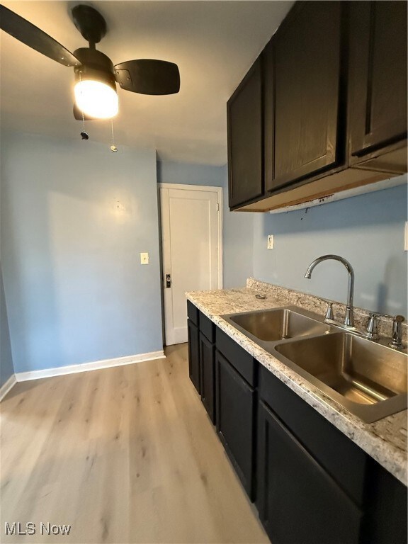 Kitchen with baseboards, light wood-type flooring, a sink, and a ceiling fan