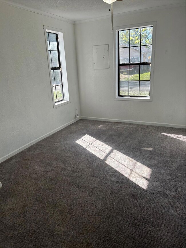 Carpeted spare room with a textured ceiling, electric panel, ceiling fan, and crown molding