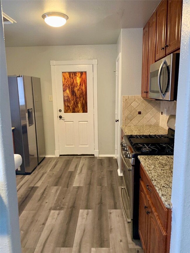 View of kitchen cabinets to ceiling, refrigerator which stays with the property. View of the back door leading to a nicely covered patio excellent for outdoor gatherings.