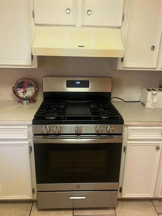 Kitchen featuring white cabinets, light tile patte