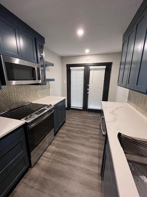 Kitchen with backsplash, stainless steel range oven, dark wood-style flooring, light stone countertops, and open shelves