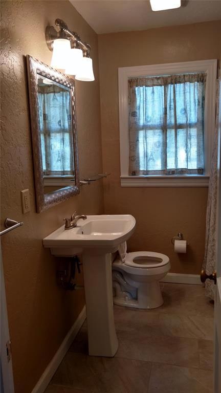 Full bathroom featuring a textured wall, curtained shower, and light tile patterned floors