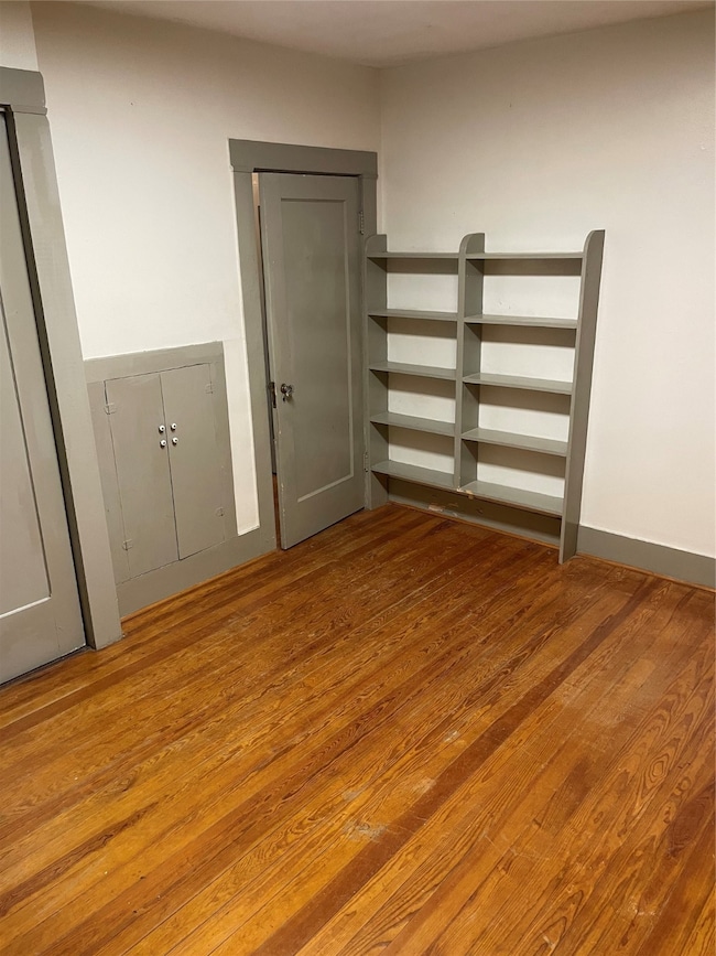 Cozy room with warm wood flooring, built-in shelvi