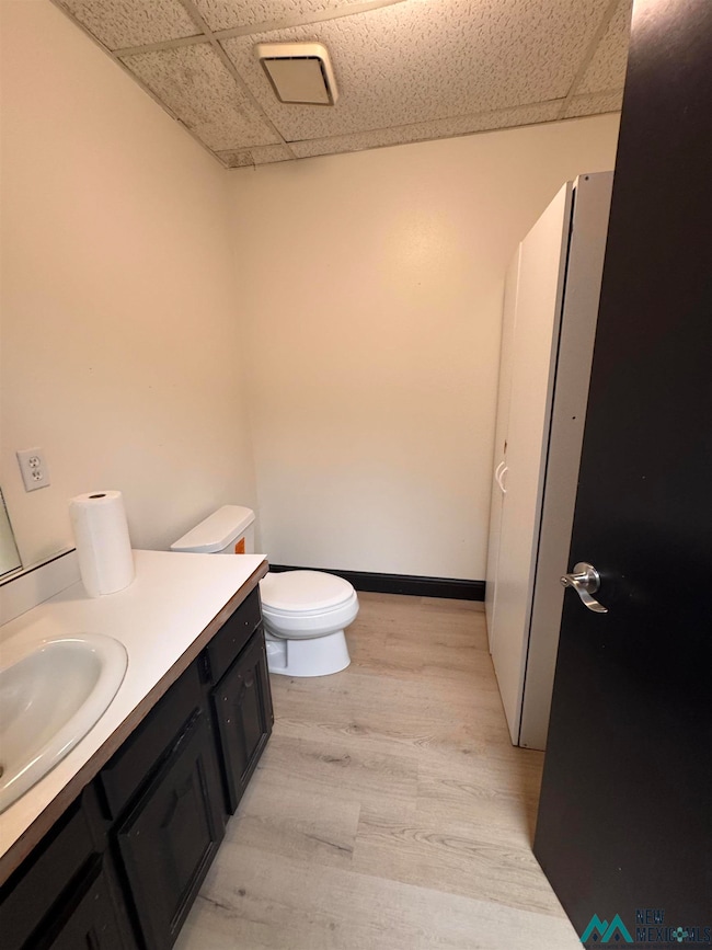 Bathroom with a drop ceiling, light wood-style floors, and vanity