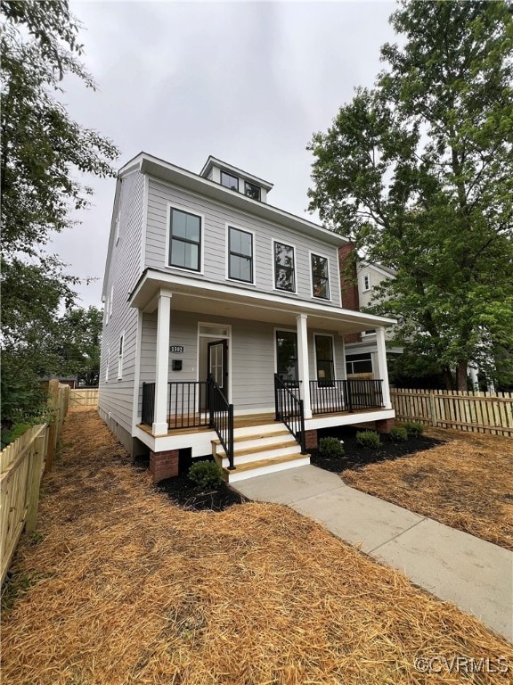 American foursquare style home featuring covered p