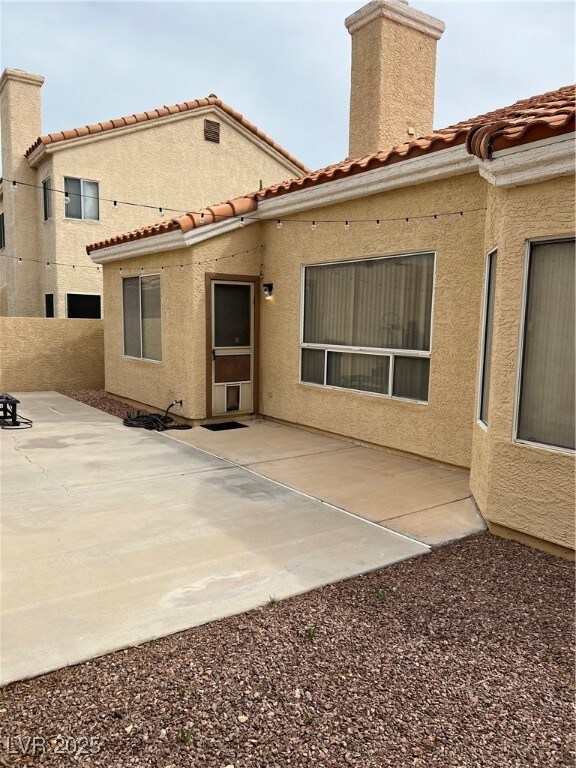 Back of house with a patio, a tiled roof, and a ch