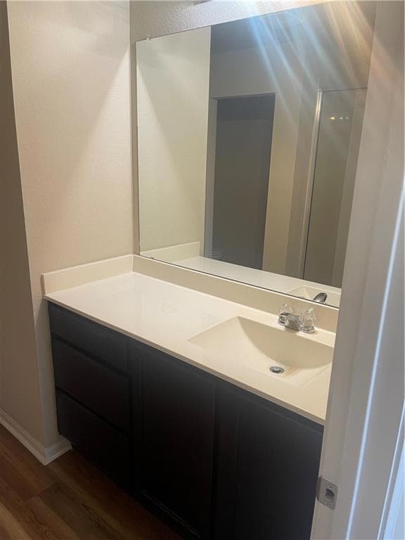 Bathroom with wood finished floors, vanity, baseb