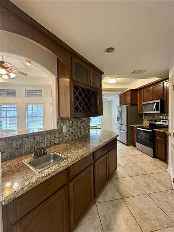 Kitchen with appliances with stainless steel finishes, a raised ceiling, backsplash, and a sink