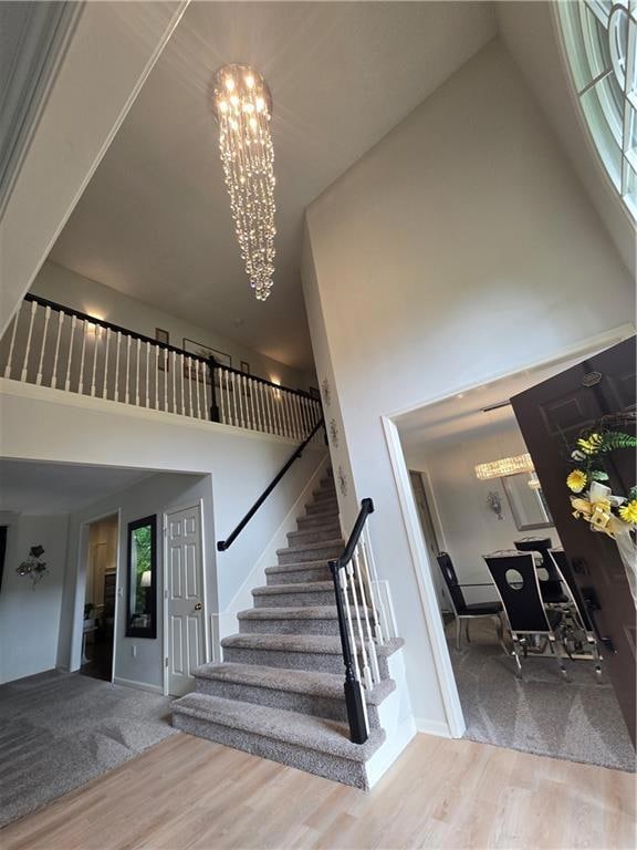 Stairway featuring a high ceiling, a chandelier, and wood finished floors