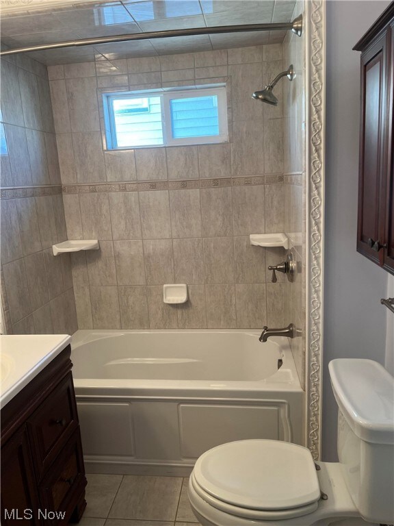 Full bathroom featuring toilet, tiled shower / bath combo, vanity, and tile flooring