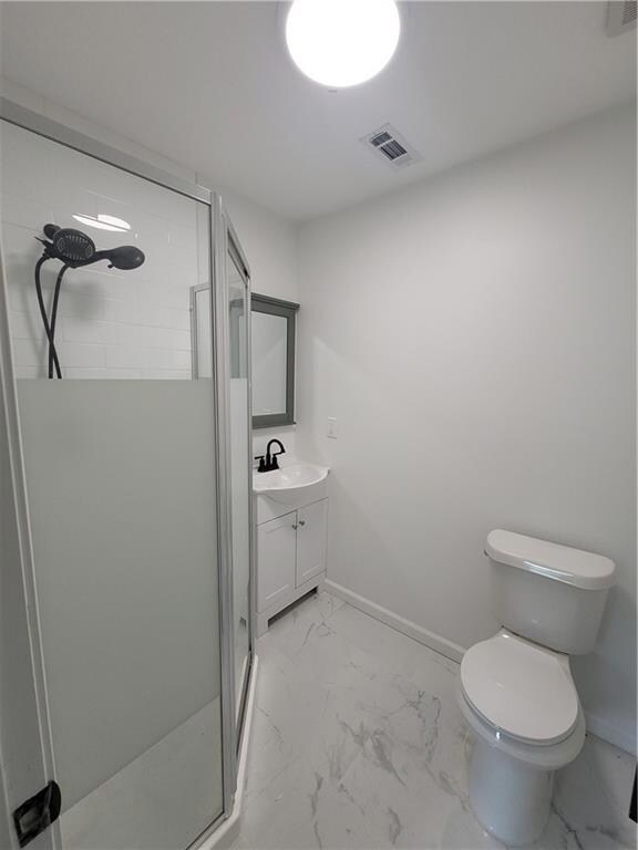 Full bath with marble look tile flooring, vanity, and a shower stall