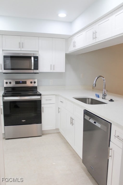 Kitchen with appliances with stainless steel finishes, white cabinetry, light tile patterned floors, and light stone countertops