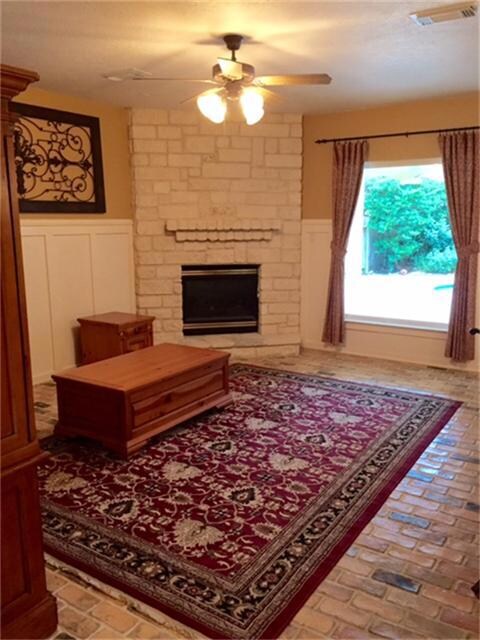 Warm and cozy den features limestone gas log fireplace perfect for cold days, large double pane window brings in outdoor view and natural light, brick flooring continues to flood throughout.