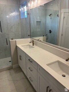 Primary bathroom with a marble finish shower, double vanity, and tile finish floors
