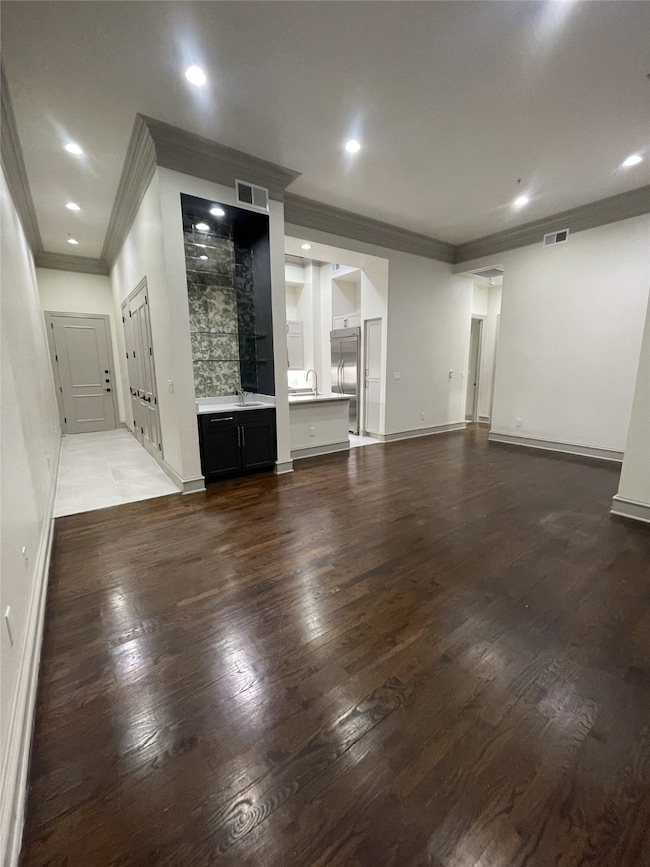 Unfurnished living room featuring crown molding, dark wood finished floors, and recessed lighting