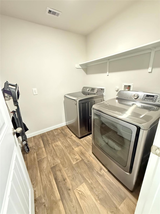 Laundry area with light wood-style flooring and independent washer and dryer
