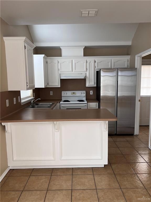 Kitchen with sink, stainless steel fridge, white electric stove, and kitchen peninsula