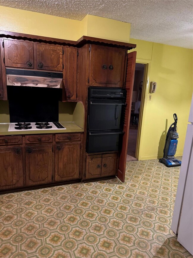 Kitchen featuring a textured ceiling, range hood, 