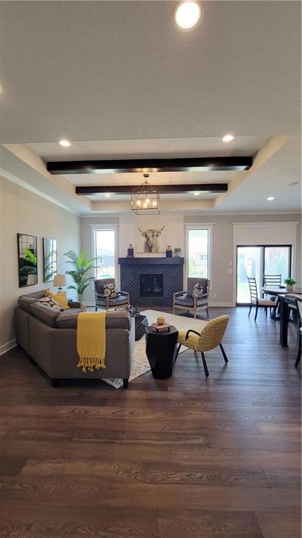 Living room with beamed ceiling, a wealth of natural light, and dark hardwood / wood-style floors