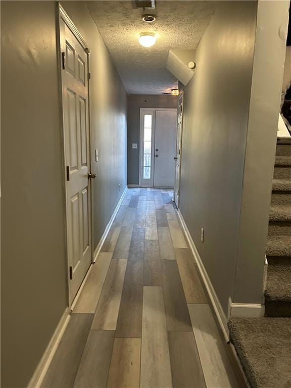 Hall featuring stairs, a textured ceiling, baseboa
