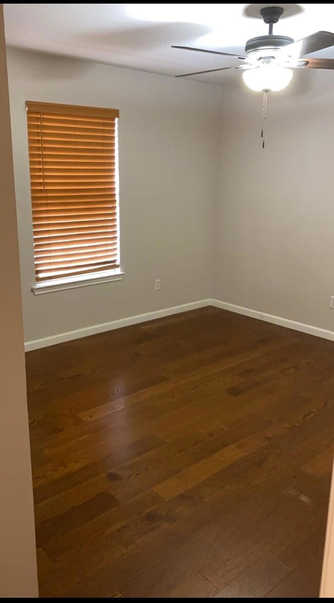 Empty room featuring ceiling fan and dark hardwood