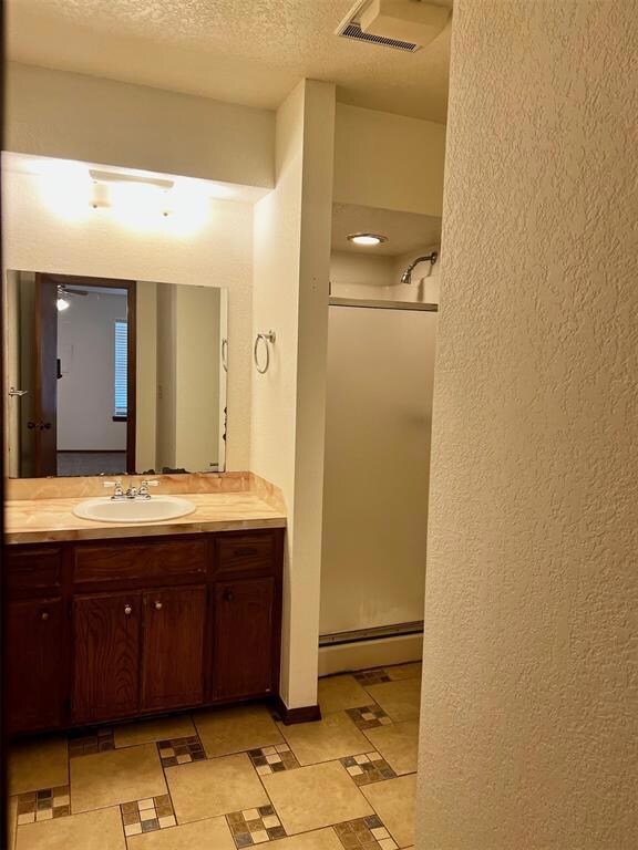 Bathroom featuring a textured ceiling, baseboard h