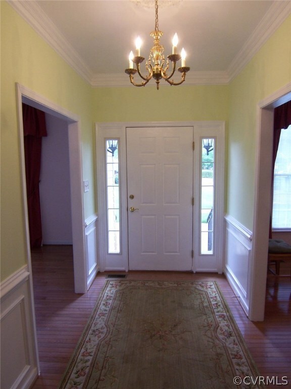 Entry foyer with hardwood floors. crown and chair