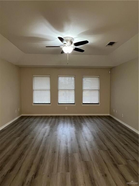 Empty room featuring dark hardwood / wood-style flooring and ceiling fan
