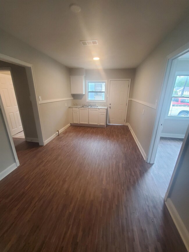 Kitchen area with dark wood-type flooring and plen