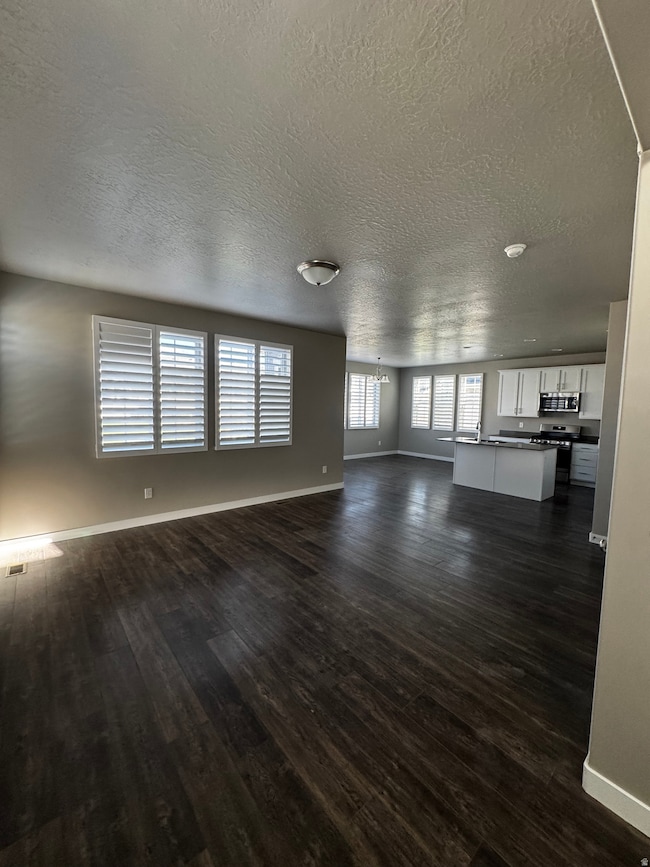 Unfurnished living room with dark wood finished floors and a textured ceiling