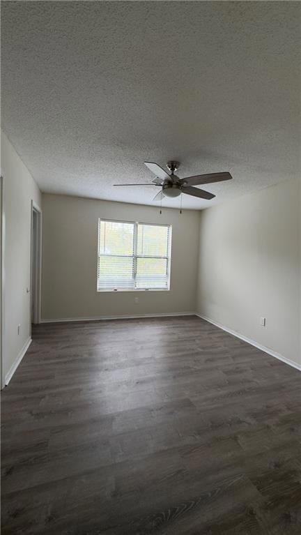 Empty room with a textured ceiling, dark wood finished floors, and ceiling fan