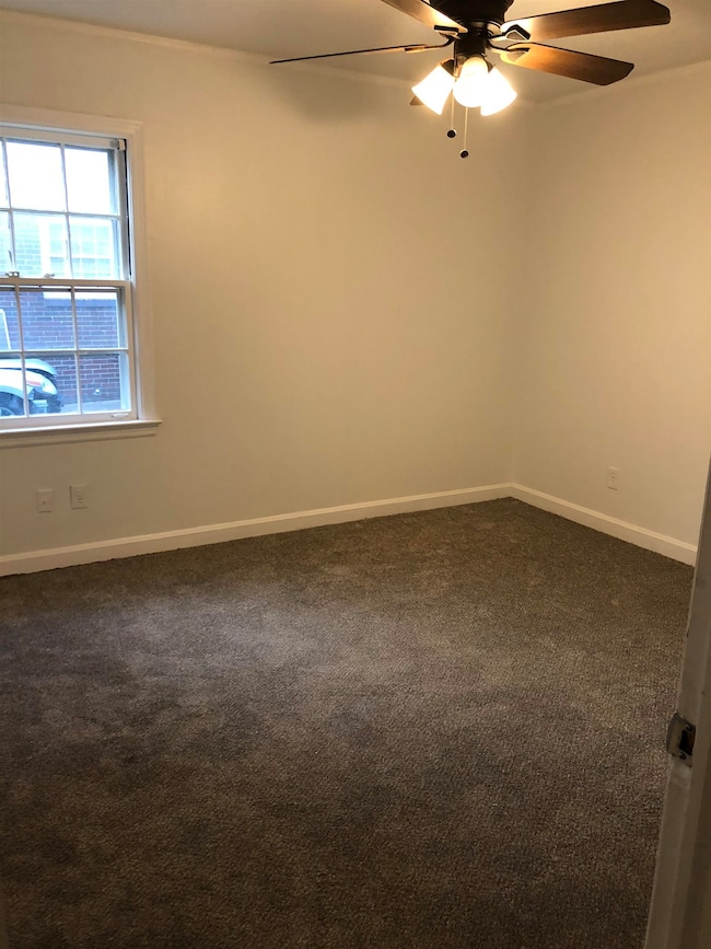 Spare room with dark colored carpet and ceiling fa
