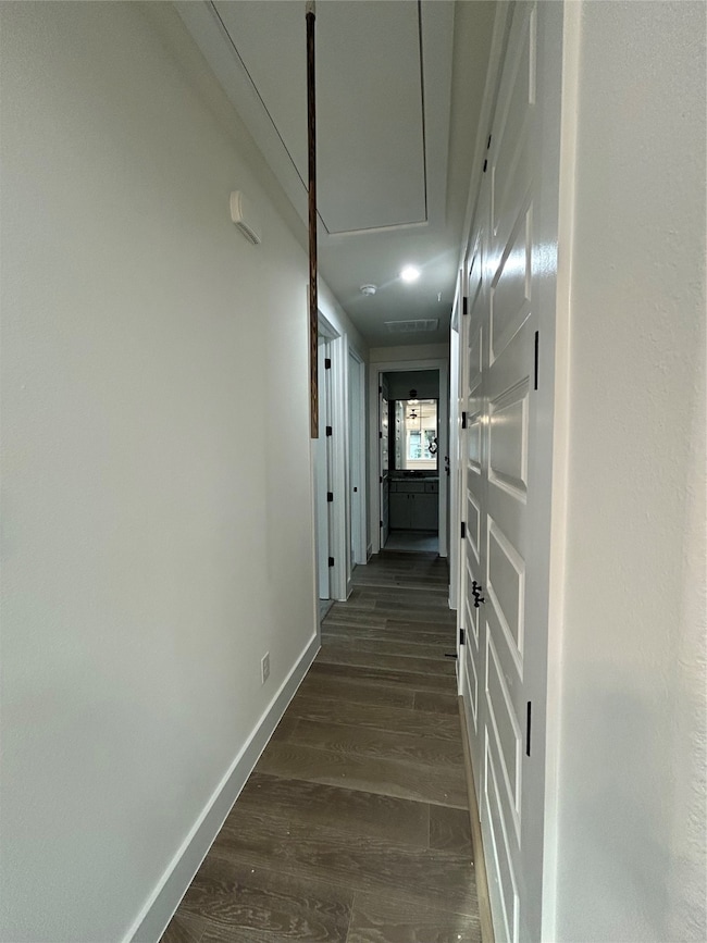Corridor with dark wood-style flooring and attic access